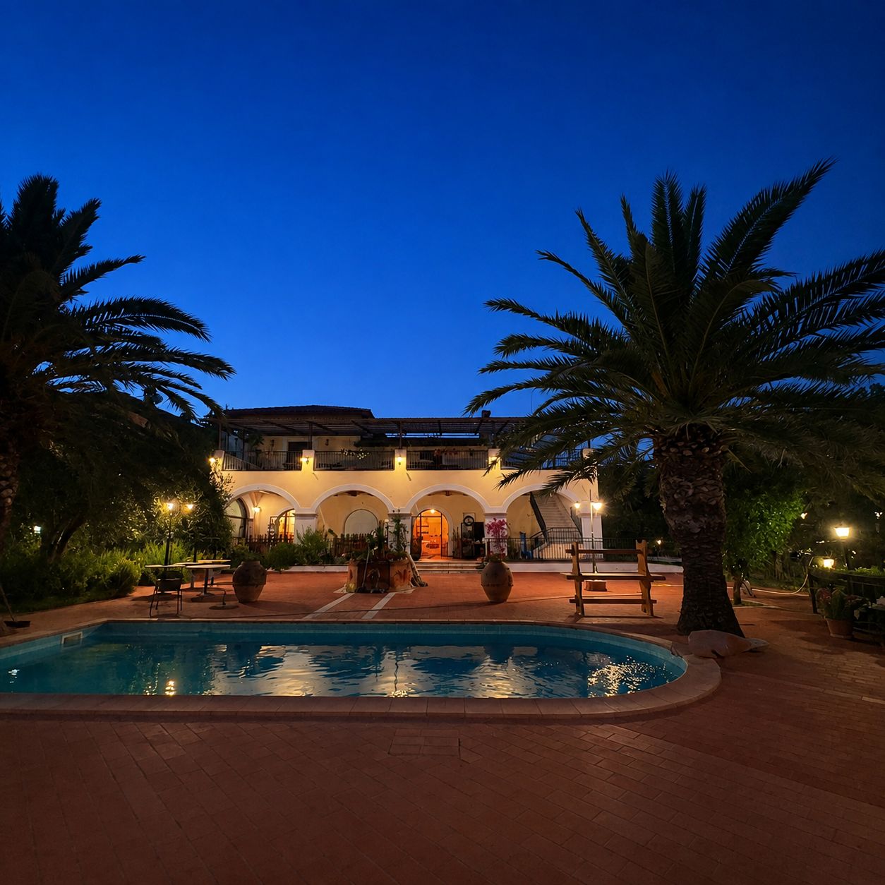 La piscina de La Palombara illuminata all'ora blu, tra le palme